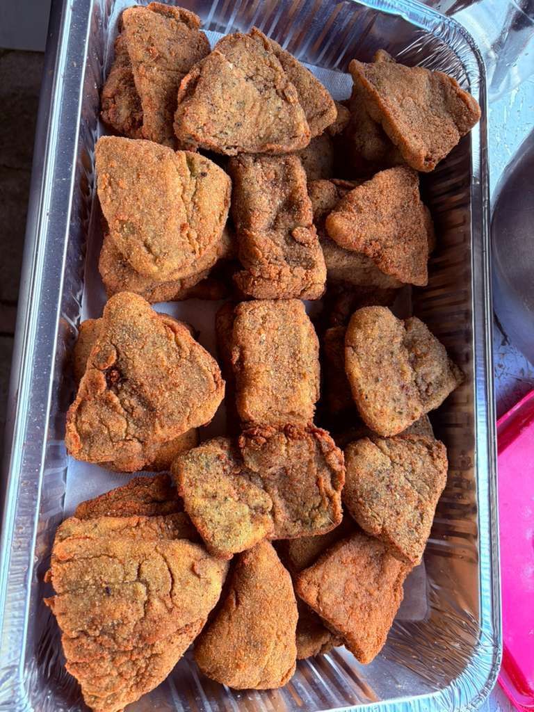 Tray of assorted golden-brown fried pastries or snacks, piled in a metal container