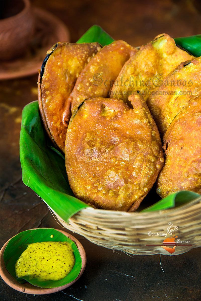 Basket of golden fried snacks on green leaves with a small bowl of dipping sauce
