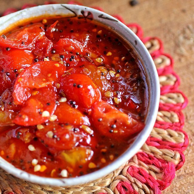 Bowl of chunky red tomato chutney with seeds, on a woven pink placemat