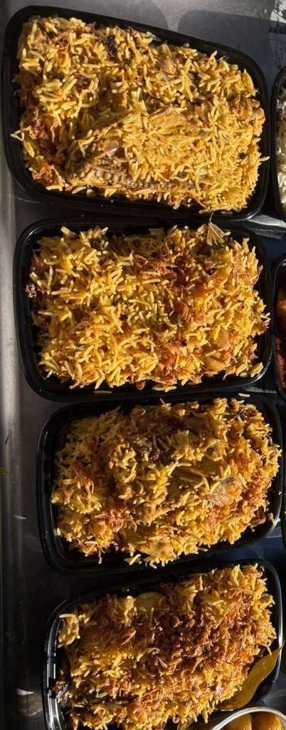 Three black meal containers filled with baked cheesy pasta, stacked vertically.