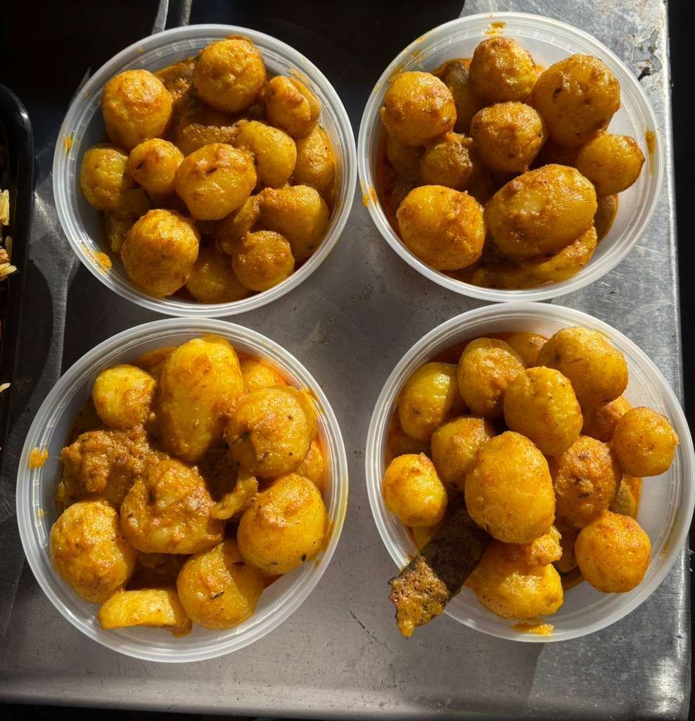 Four clear plastic cups filled with spiced fried snacks on a metal tray