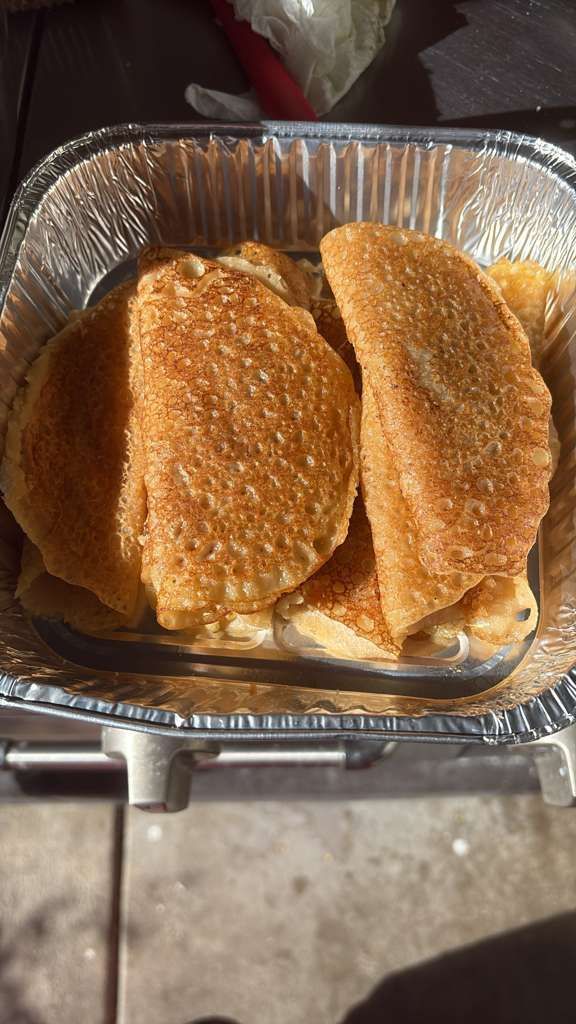 Foil tray with three breaded fried cutlets on a stovetop