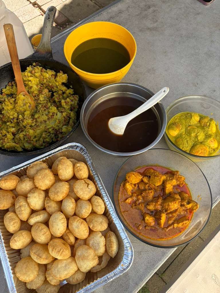 Overhead view of assorted prepared foods in trays and bowls on a concrete surface.