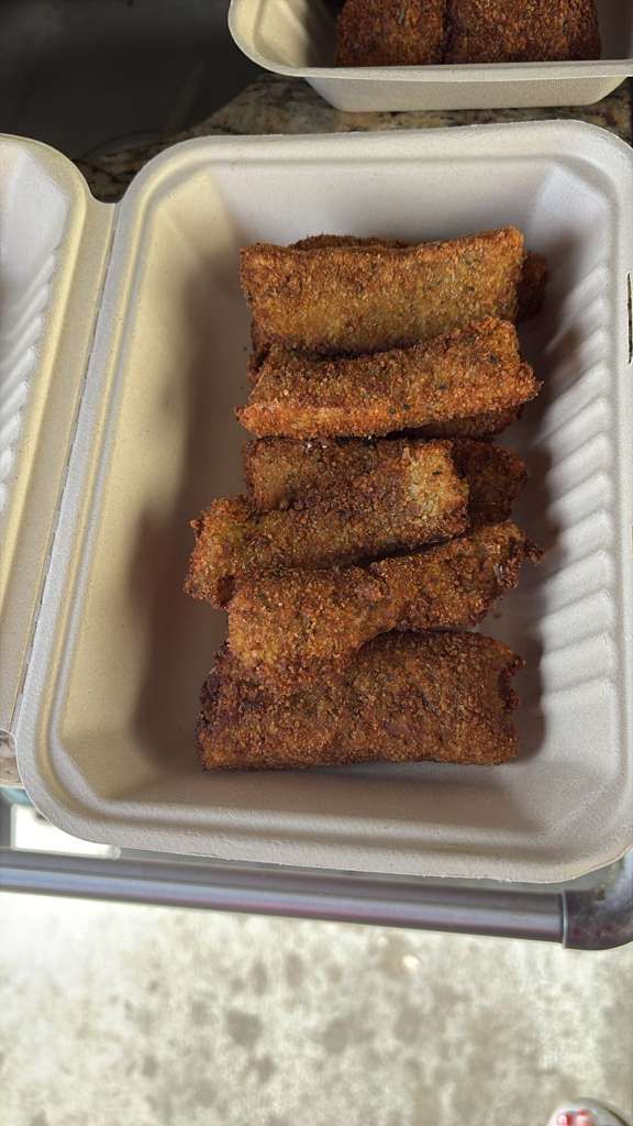 Container of fried breaded sticks in a white foam takeout tray