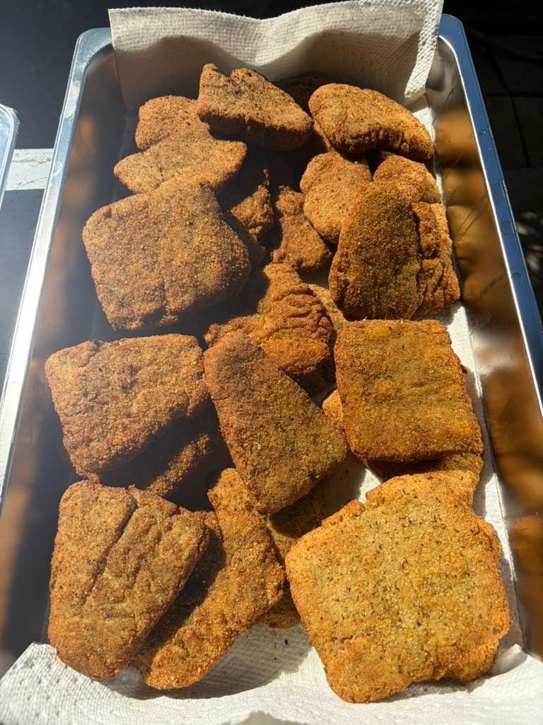 Tray of crispy breaded chicken pieces on foil-lined paper in a takeout box