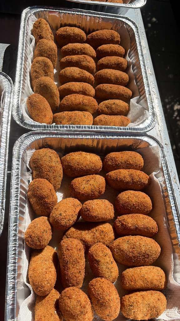 Two foil trays filled with breaded fried croquettes, neatly arranged.