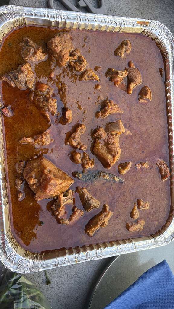 Foil takeout tray of brown stew with chunks of meat, seen from above