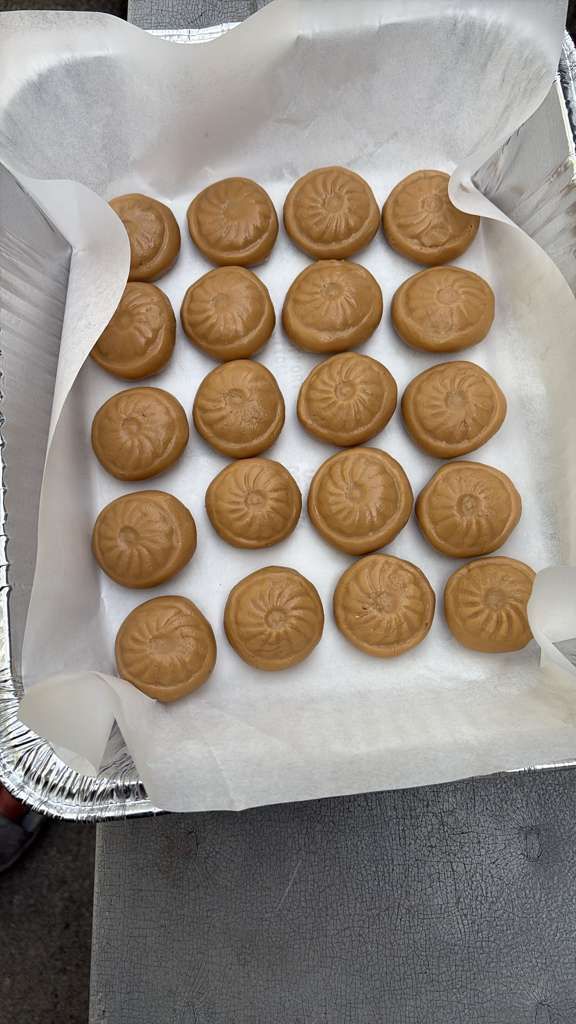 Tray of round tan cookies arranged in rows on white parchment paper