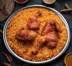 Platter of spiced rice topped with roasted chicken pieces, seen from above.