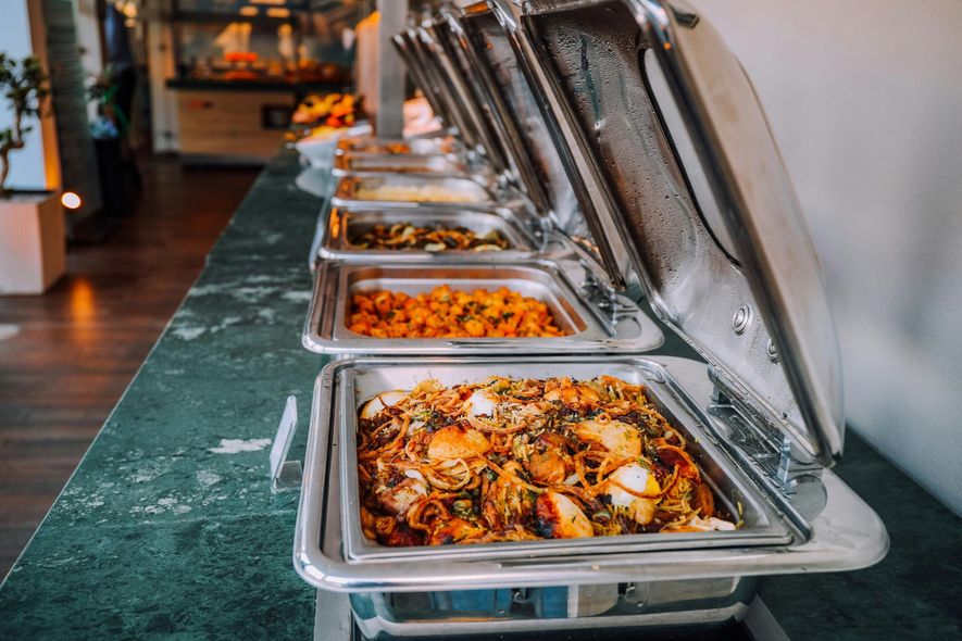 Buffet line with stainless steel chafing dishes of hot food on a long table