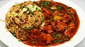 Plate of noodles and vegetables topped with red sauce on a white dish