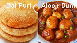 Dal Puri and aloo’r dum on a plate, golden fried bread beside spiced potato curry