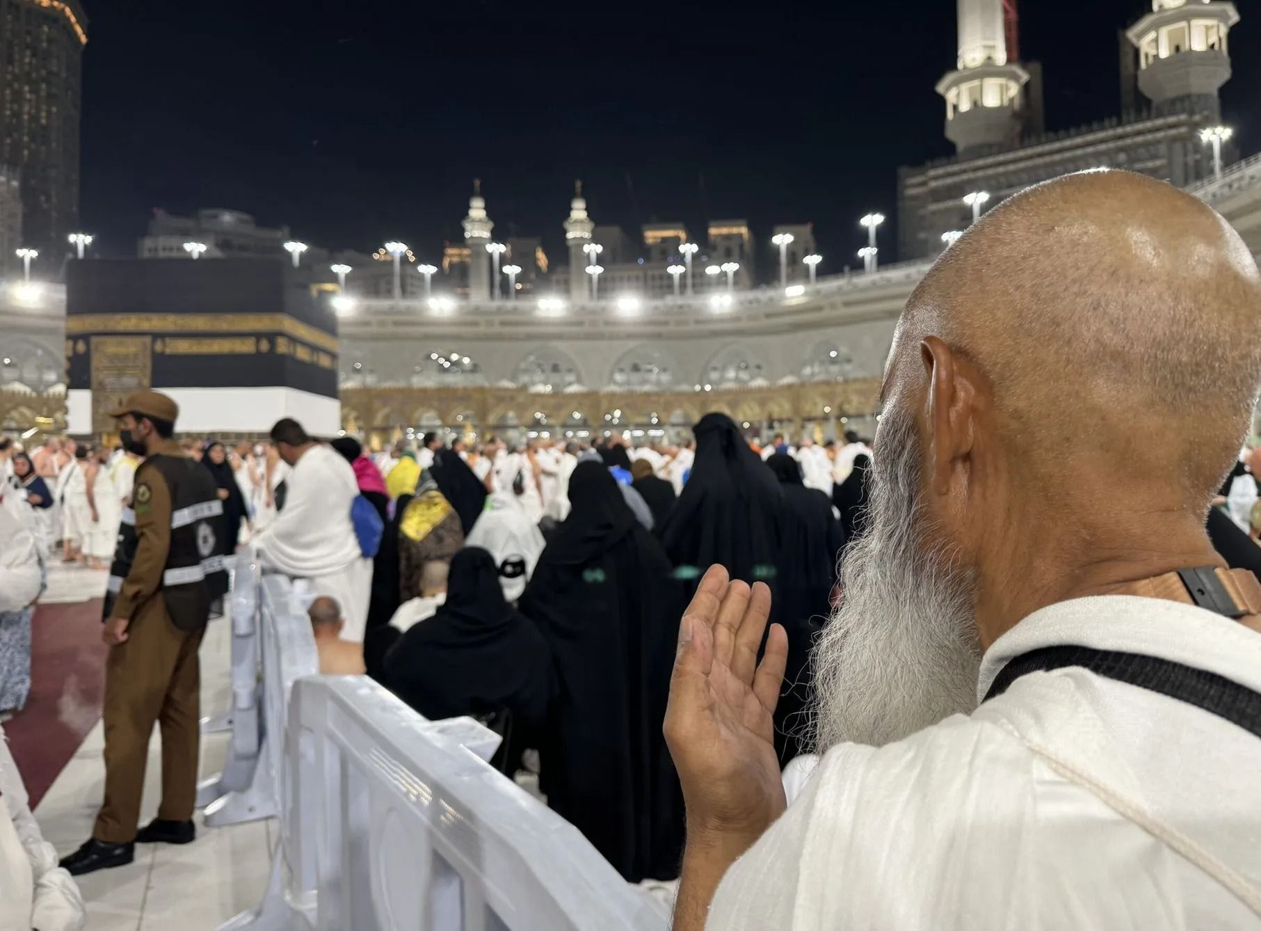 Pelgrims in witte en zwarte gewaden bidden 's nachts bij de Kaaba in Mekka.