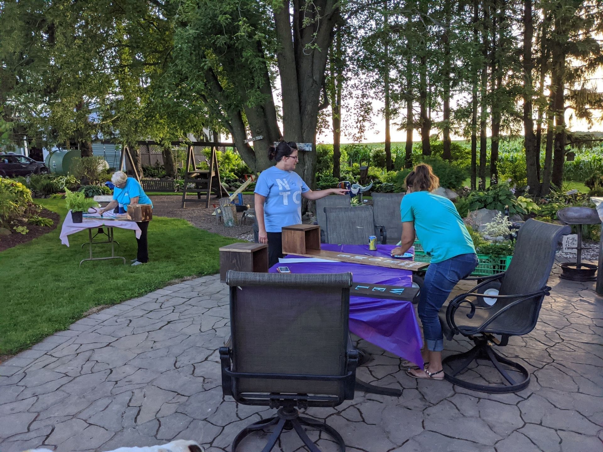 A group of people are standing around a table with a purple table cloth.