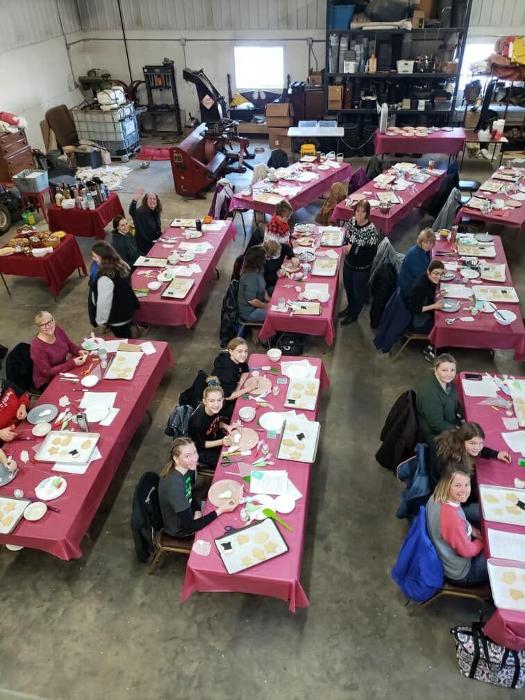 A group of people are sitting at long tables in a room.