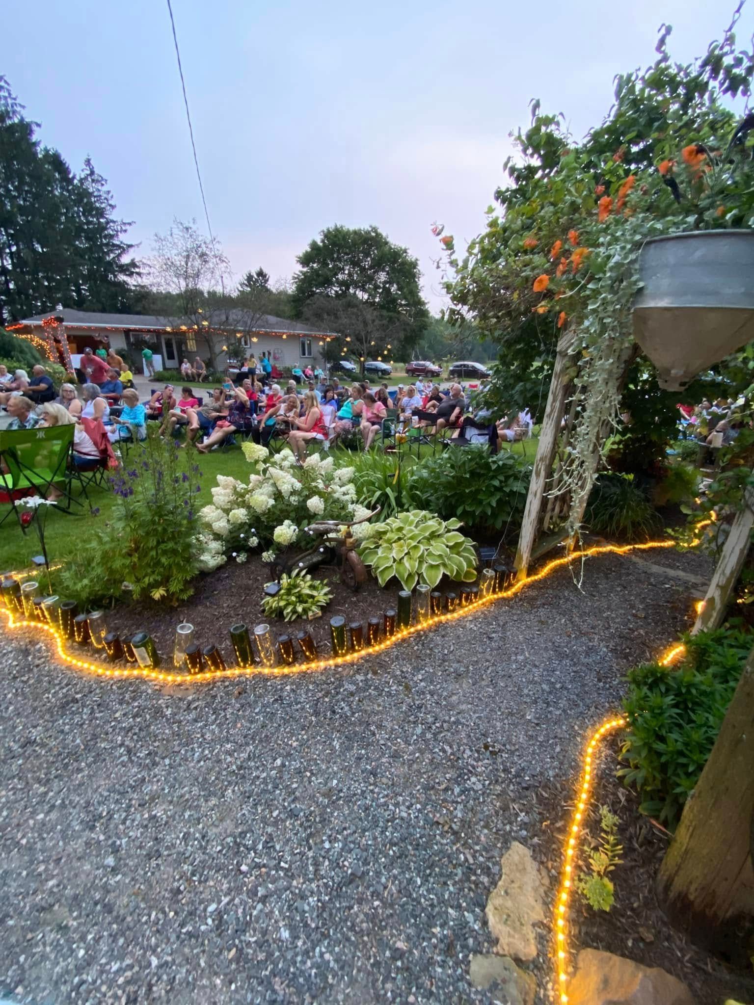 A group of people are sitting in a garden watching a movie.