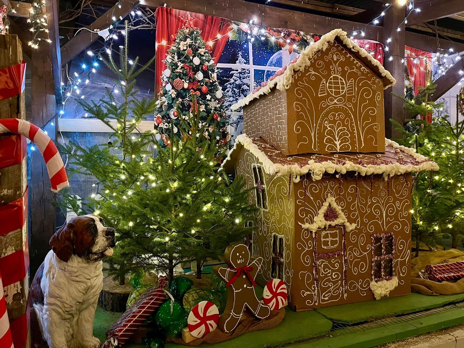 A dog is sitting in front of a gingerbread house.