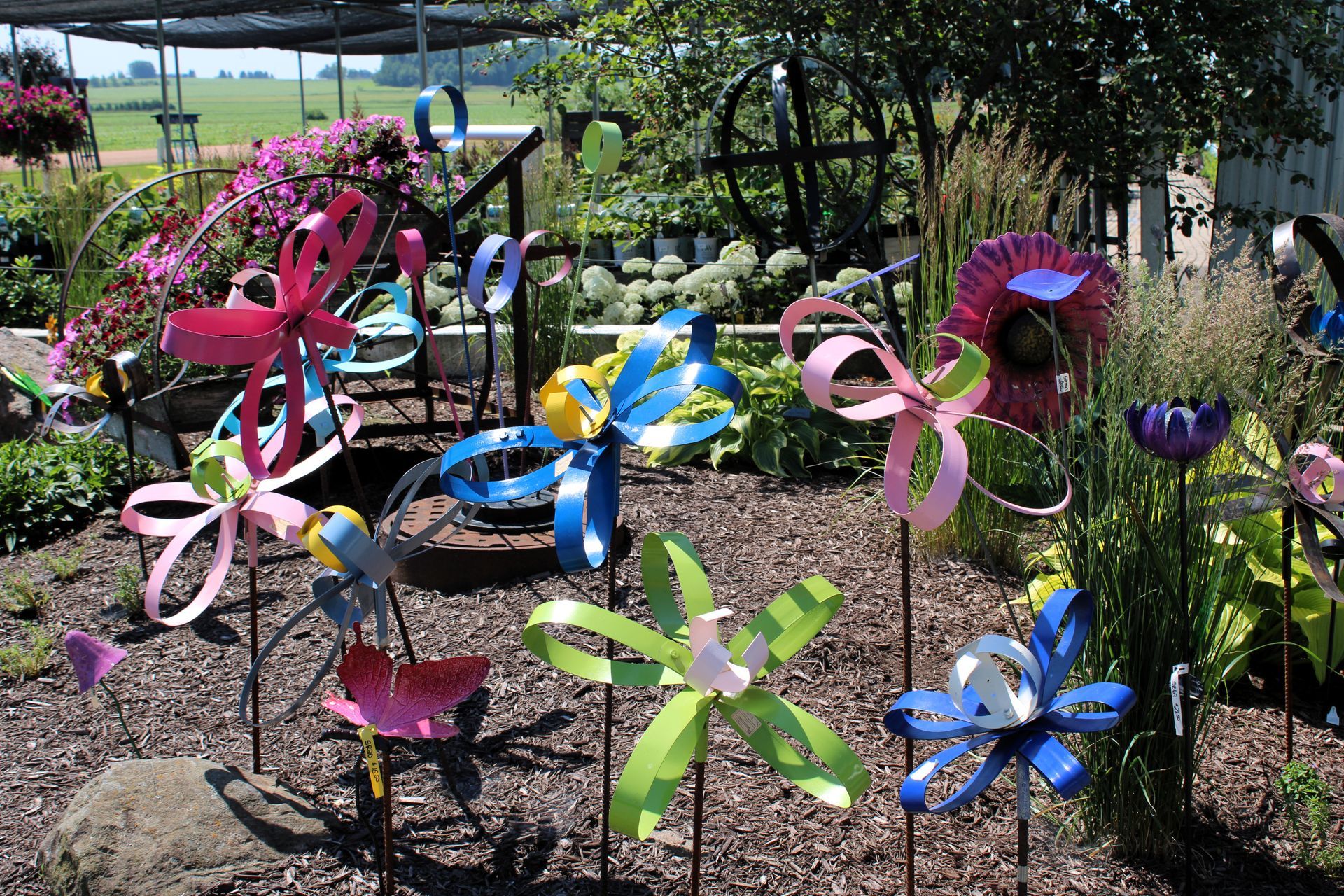Colorful metal garden art, flowers and pinwheels, in a garden setting.