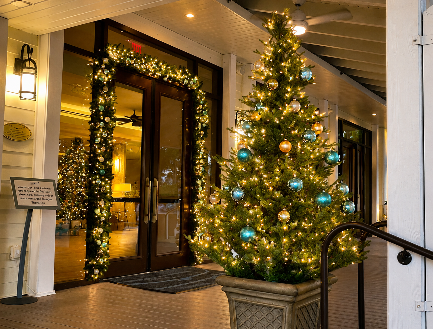 Festively lit building entrance with a decorated Christmas tree and holiday garland on the porch