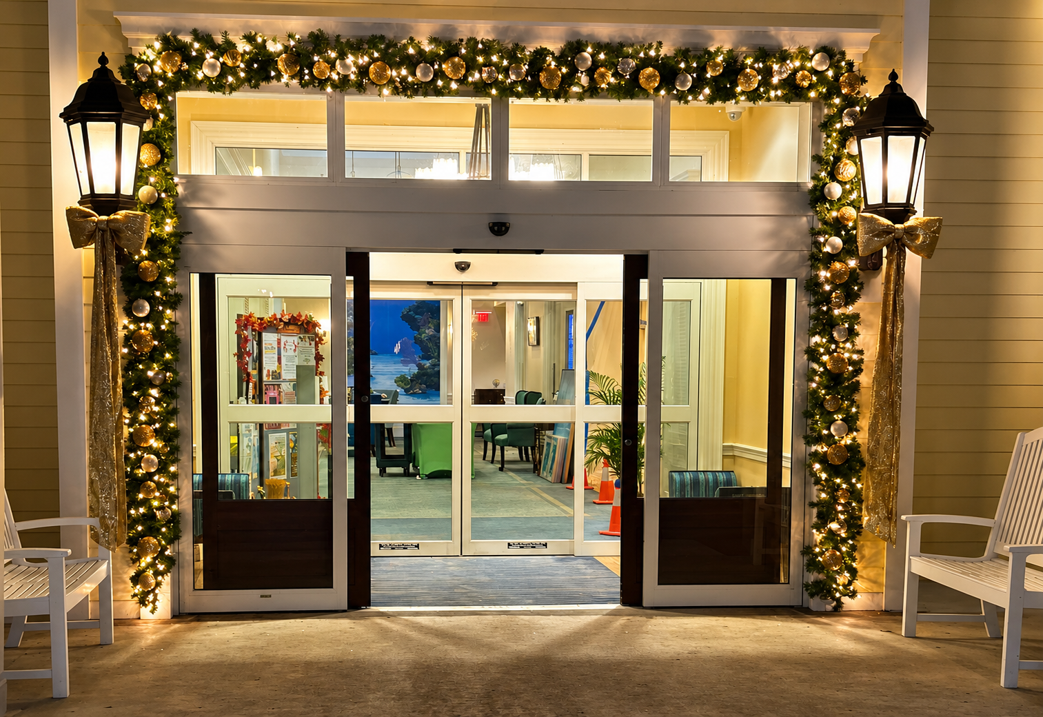 Festively lit storefront entrance with glass doors, wreaths, and holiday garlands at night