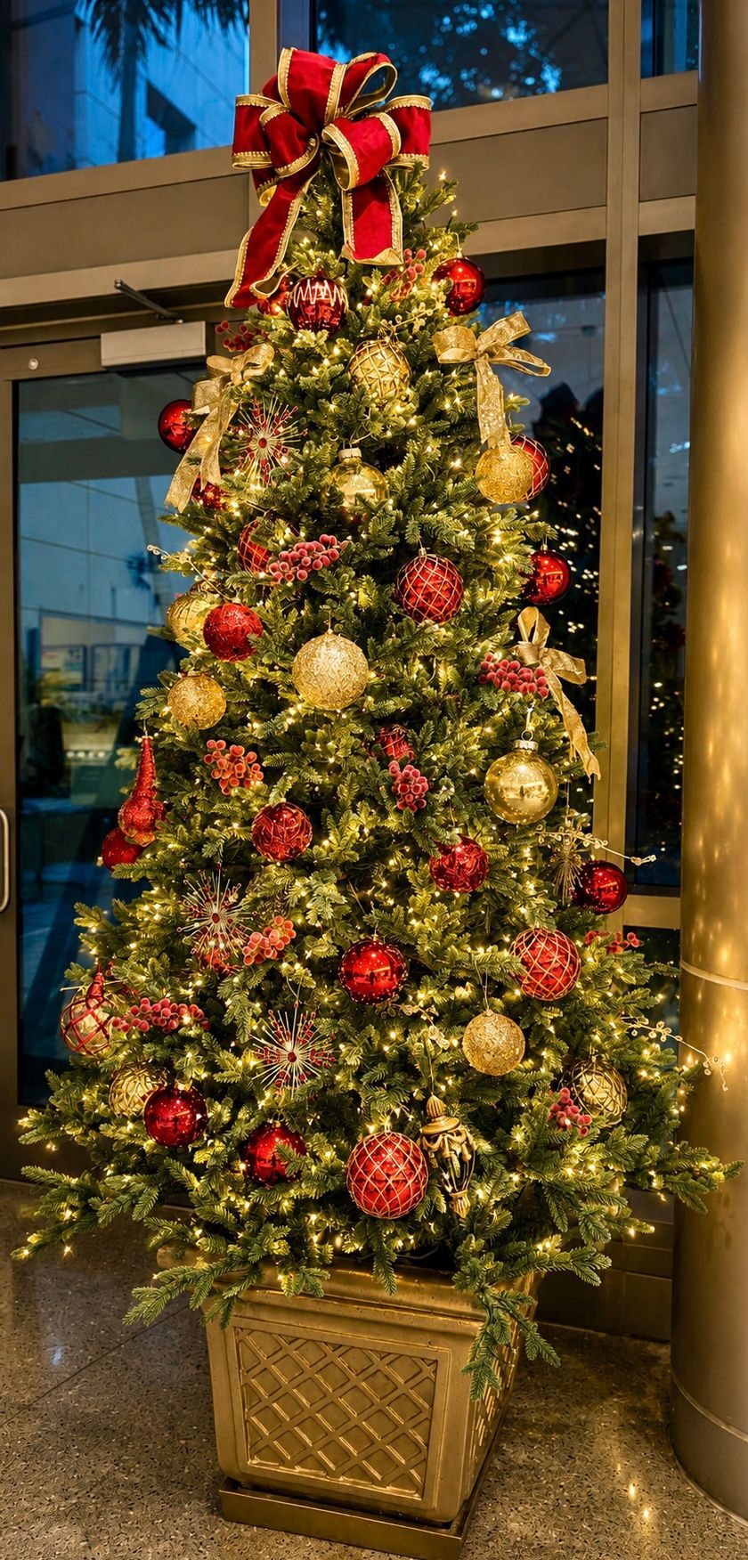 Decorated Christmas tree with red and gold ornaments and lights in a lobby
