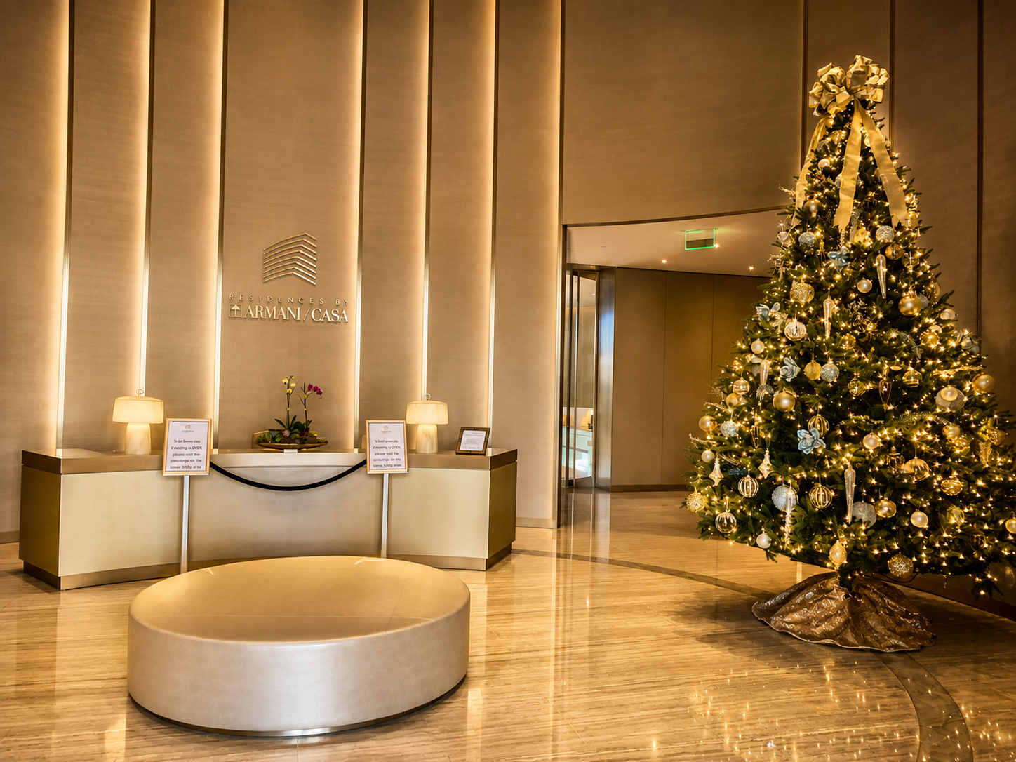 Elegant hotel lobby with a lit Christmas tree, marble floor, and circular bench near the entrance