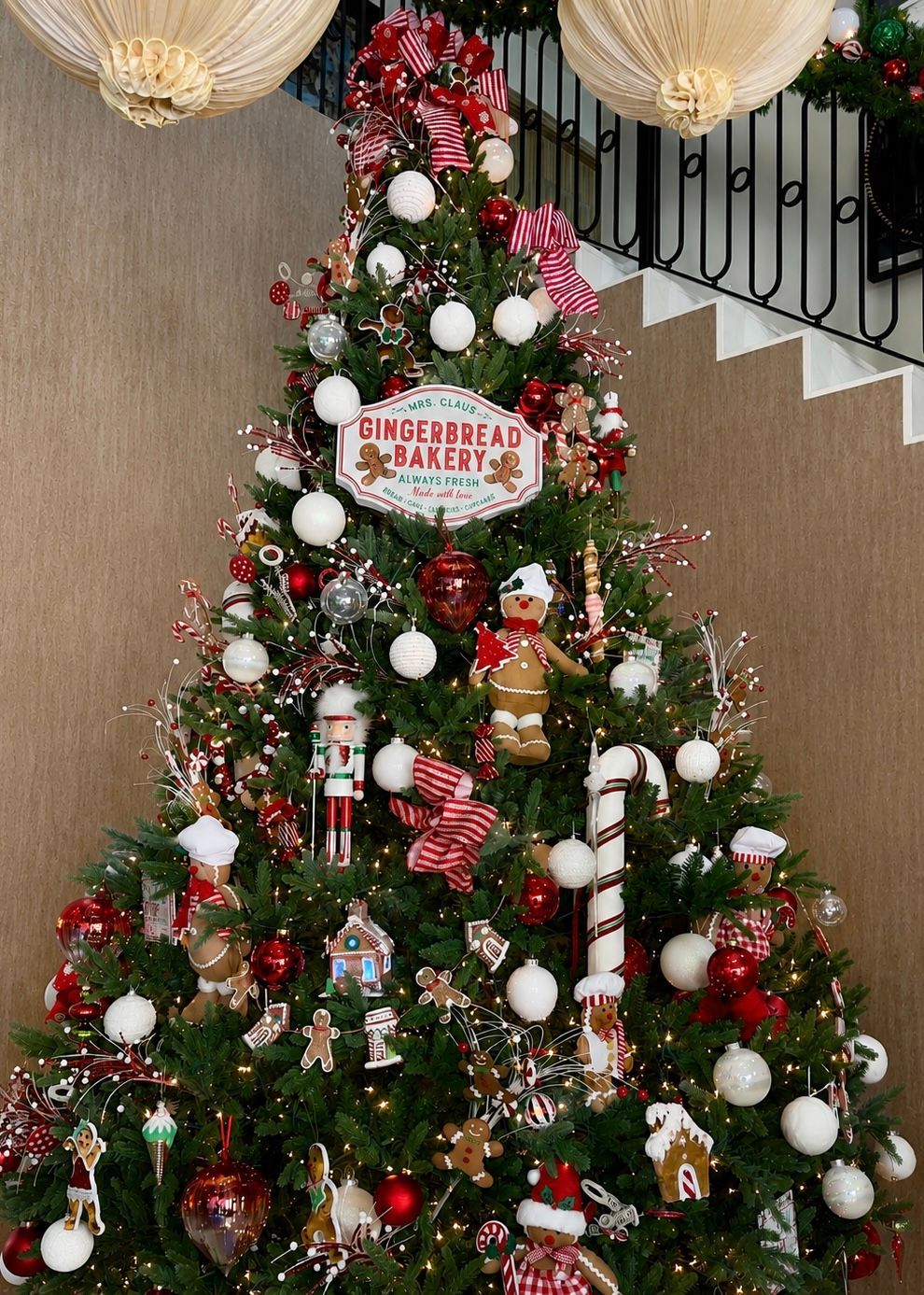Decorated Christmas tree with red, white, and gold ornaments and a “Merry Christmas” sign indoors