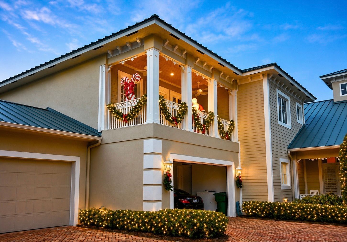 Two-story house with beige siding, blue roof, and holiday decorations on the balcony and porch.