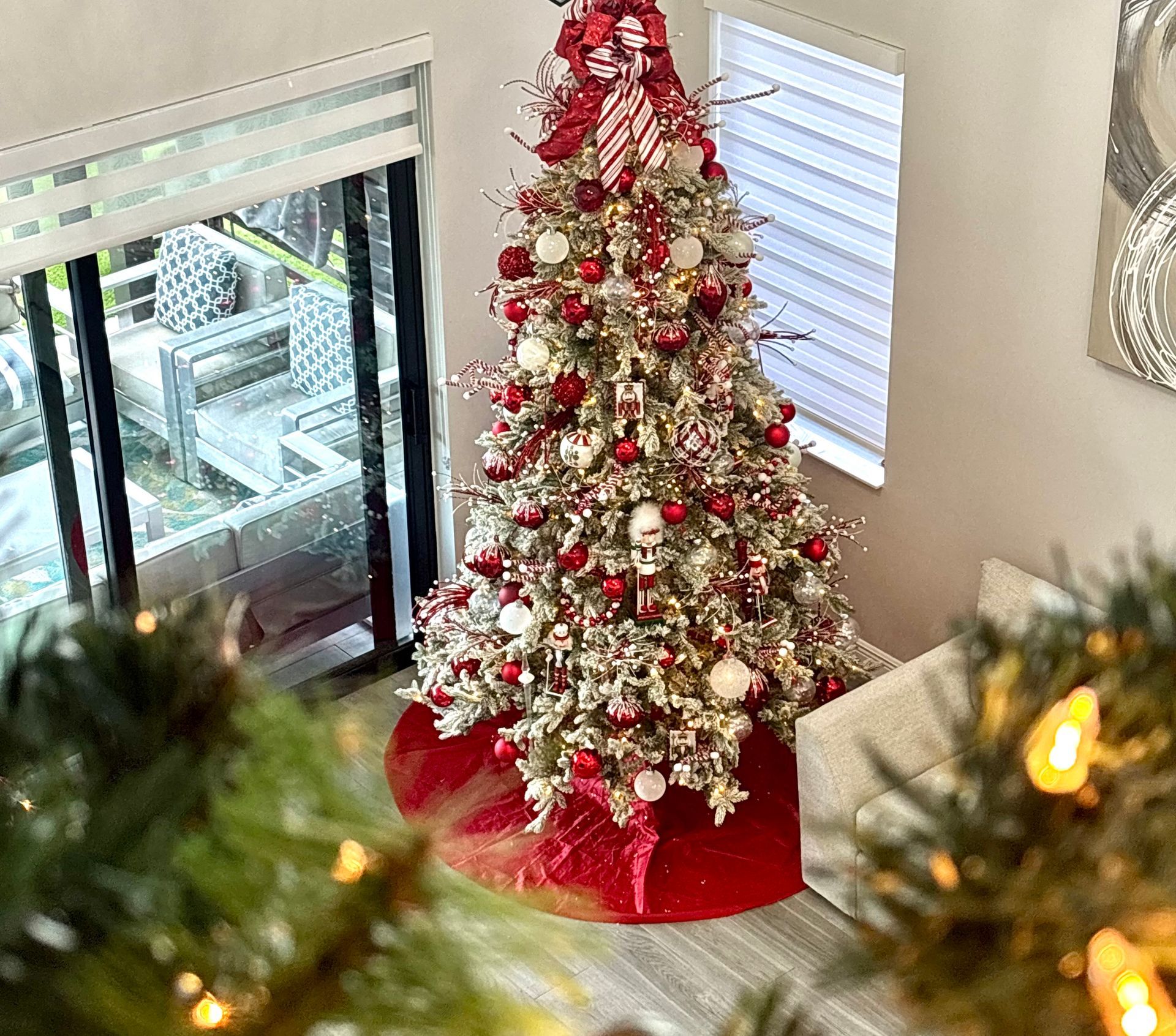 Decorated Christmas tree with red and white ornaments in a living room by a window