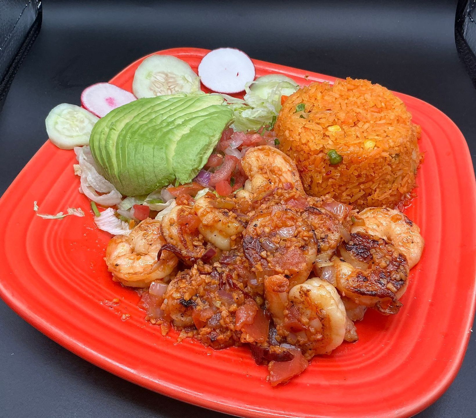 A plate of grilled shrimp with rice, avocado, and vegetables.