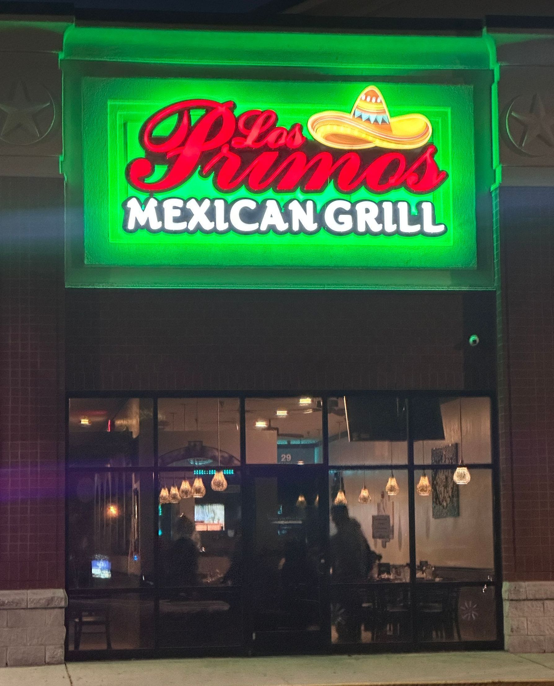 Los Primos Mexican Grill storefront with green neon sign.