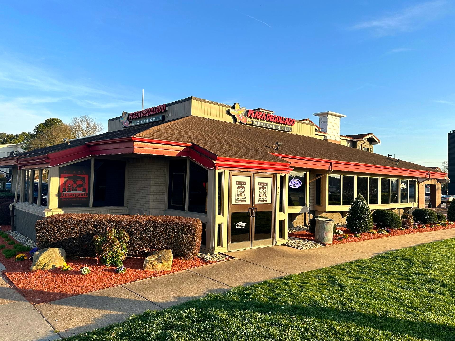 Restaurant building with red trim, brick exterior, and a lawn.