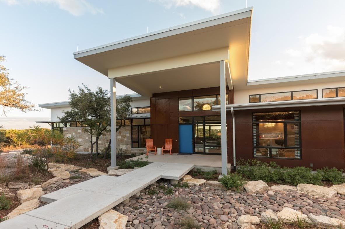 Modern home with brown and white siding, light blue front door, concrete walkway, and rock landscaping.