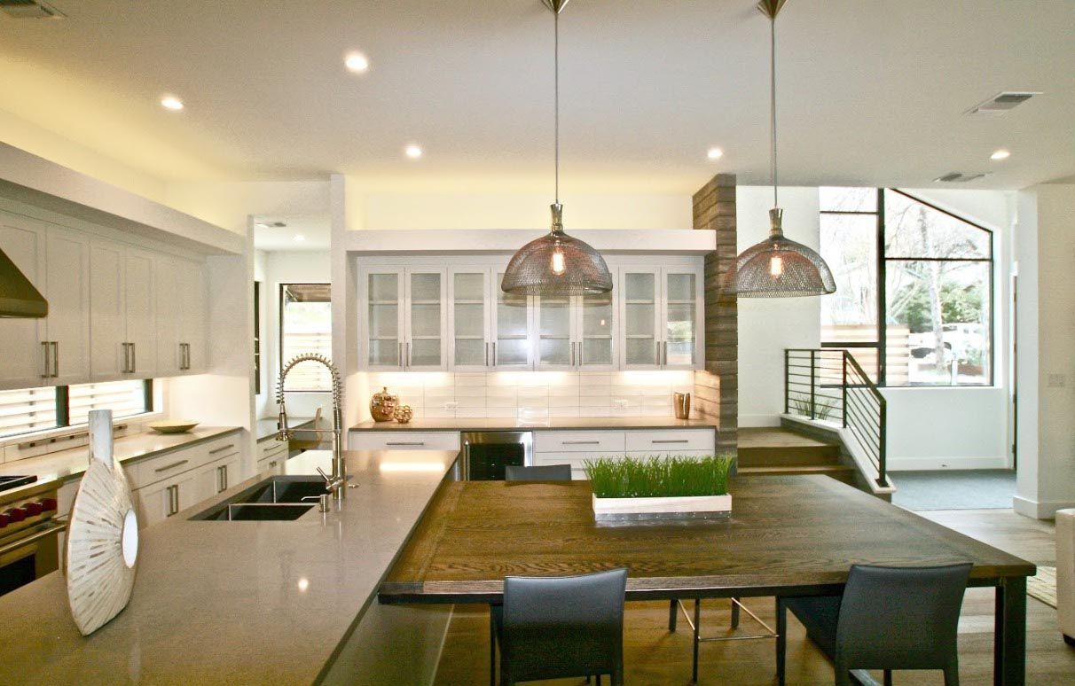 Modern kitchen with island, pendant lights, and stainless steel appliances.