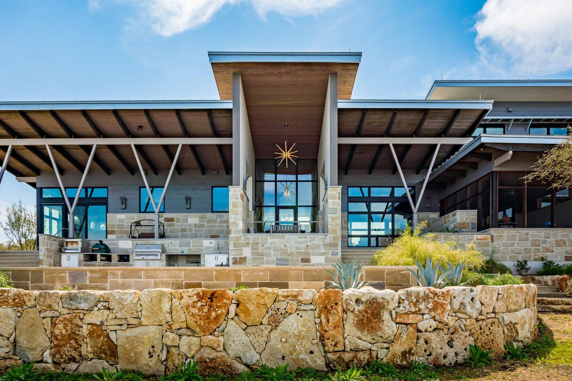 Modern home with stone facade and sunburst decor on a sunny day.