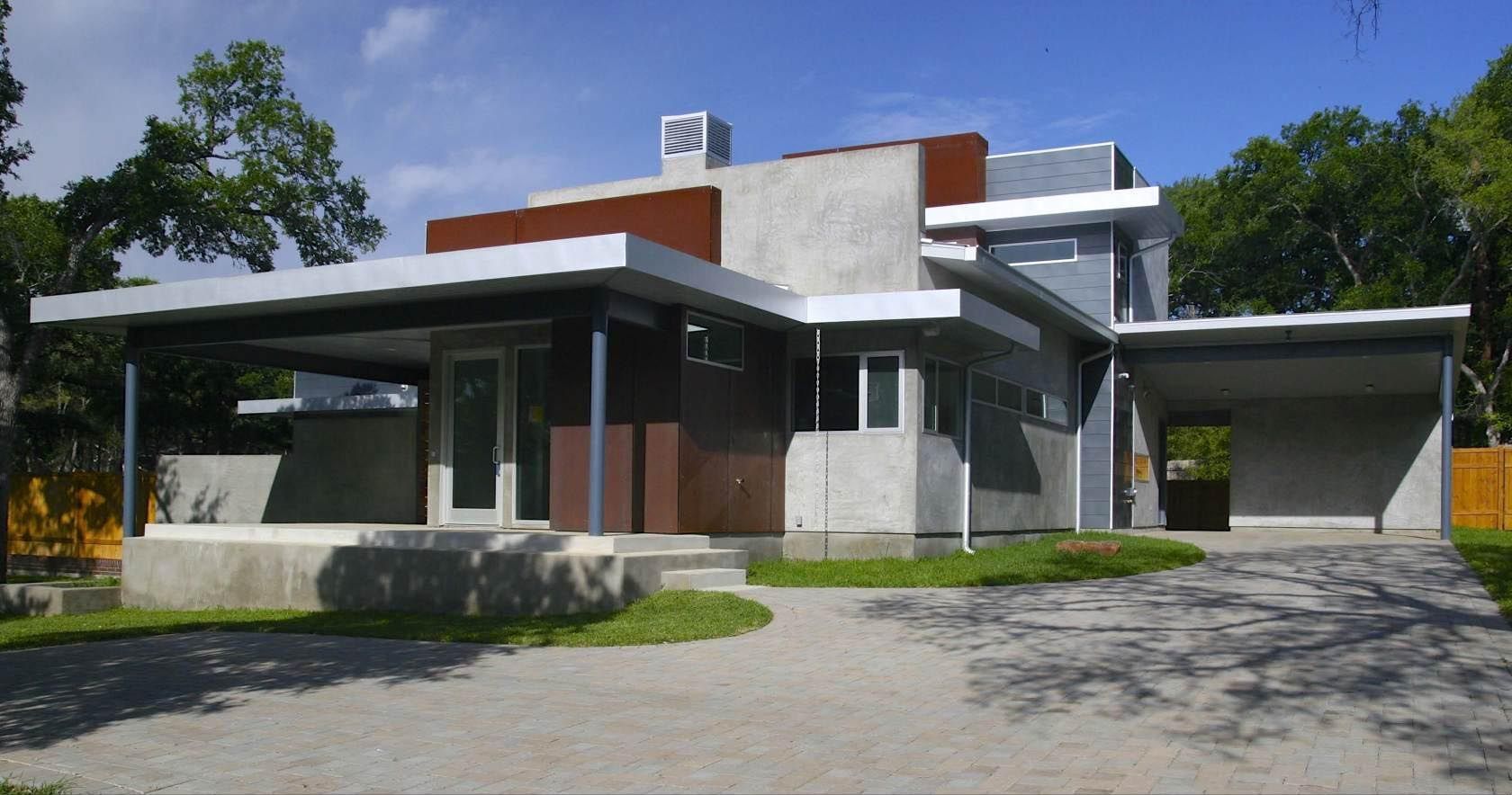 Modern home with flat roofs, concrete, and metal accents; a driveway and yard.