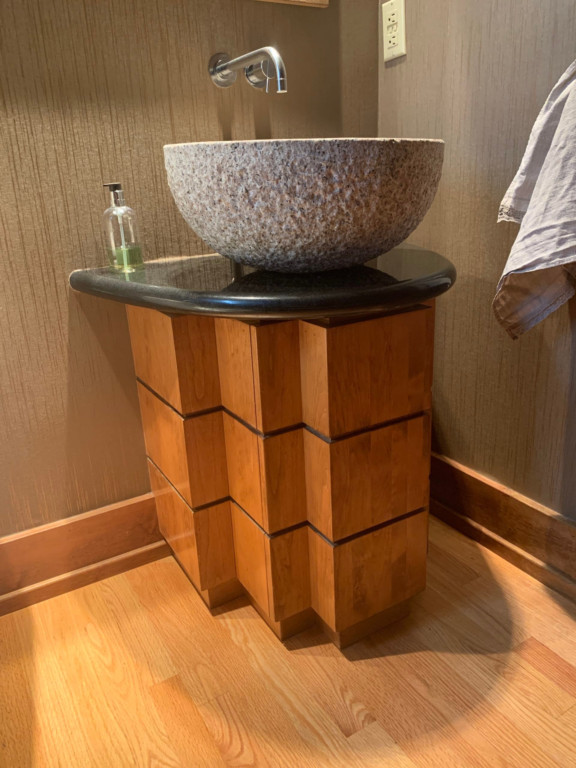 A bathroom with a stone sink on a wooden stand