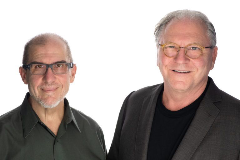 Two men are standing next to each other and smiling for the camera.