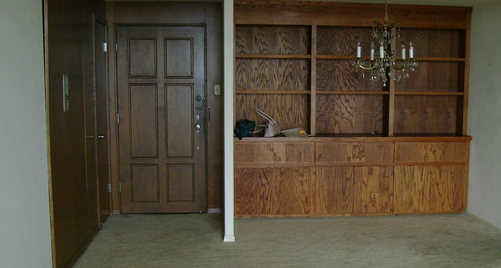A dark wood door and built-in bookshelf in a room with a chandelier.
