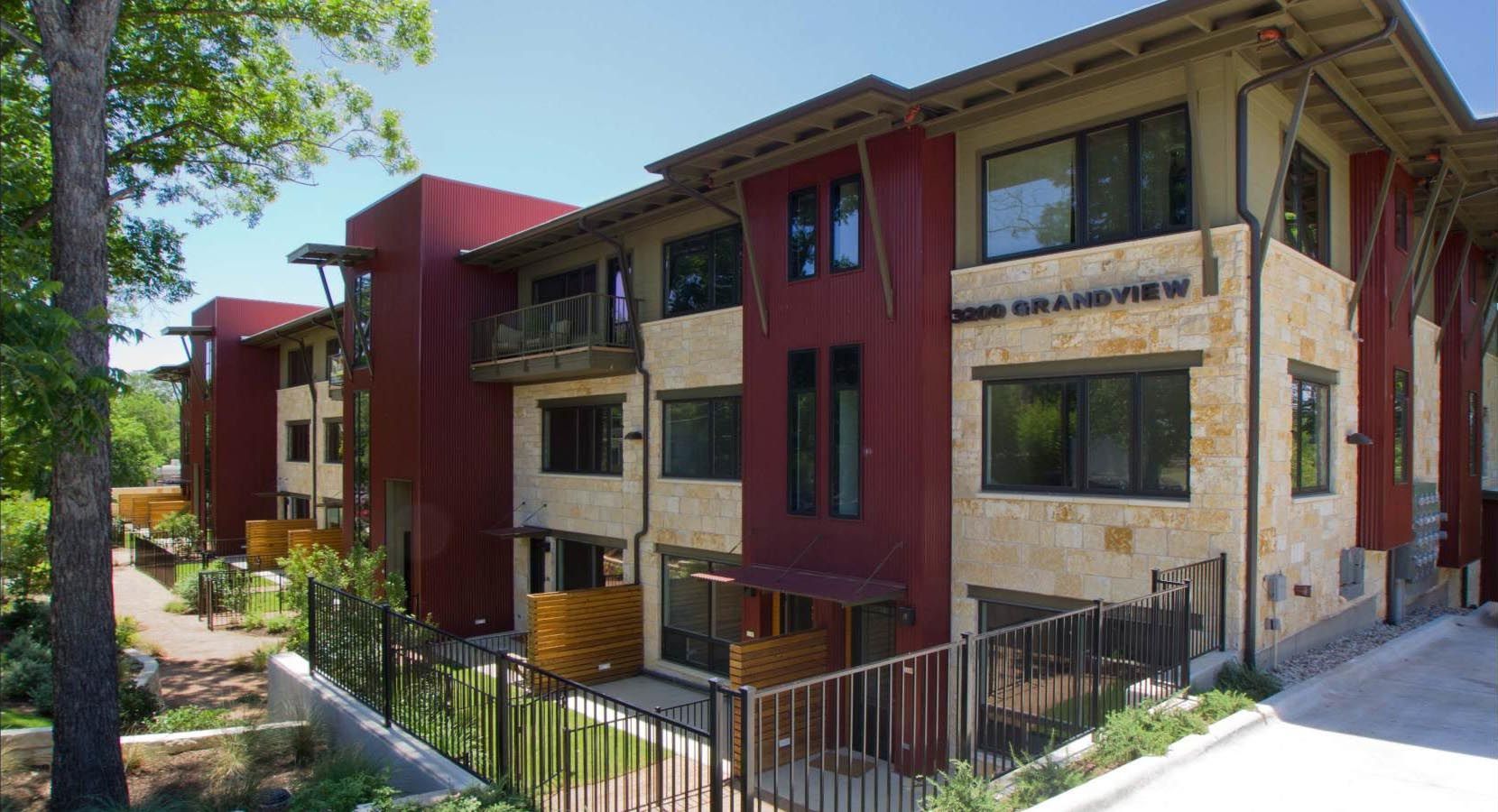 Multi-story building with red siding, stone facade, and balconies.