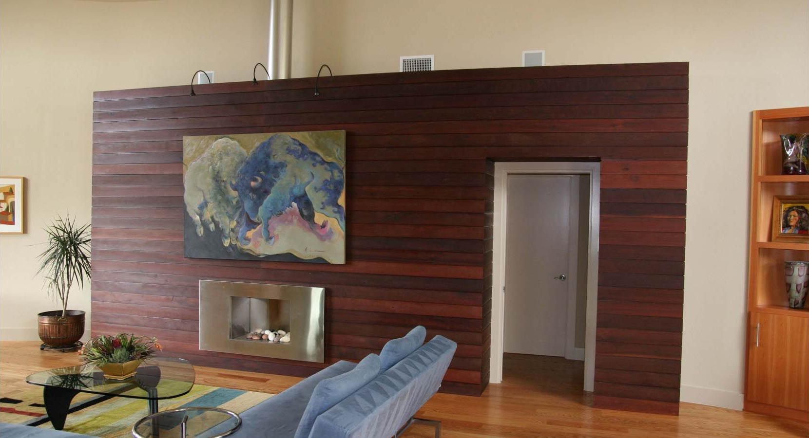 Living room with a dark wood wall, fireplace, art, doorway, and blue sofa.
