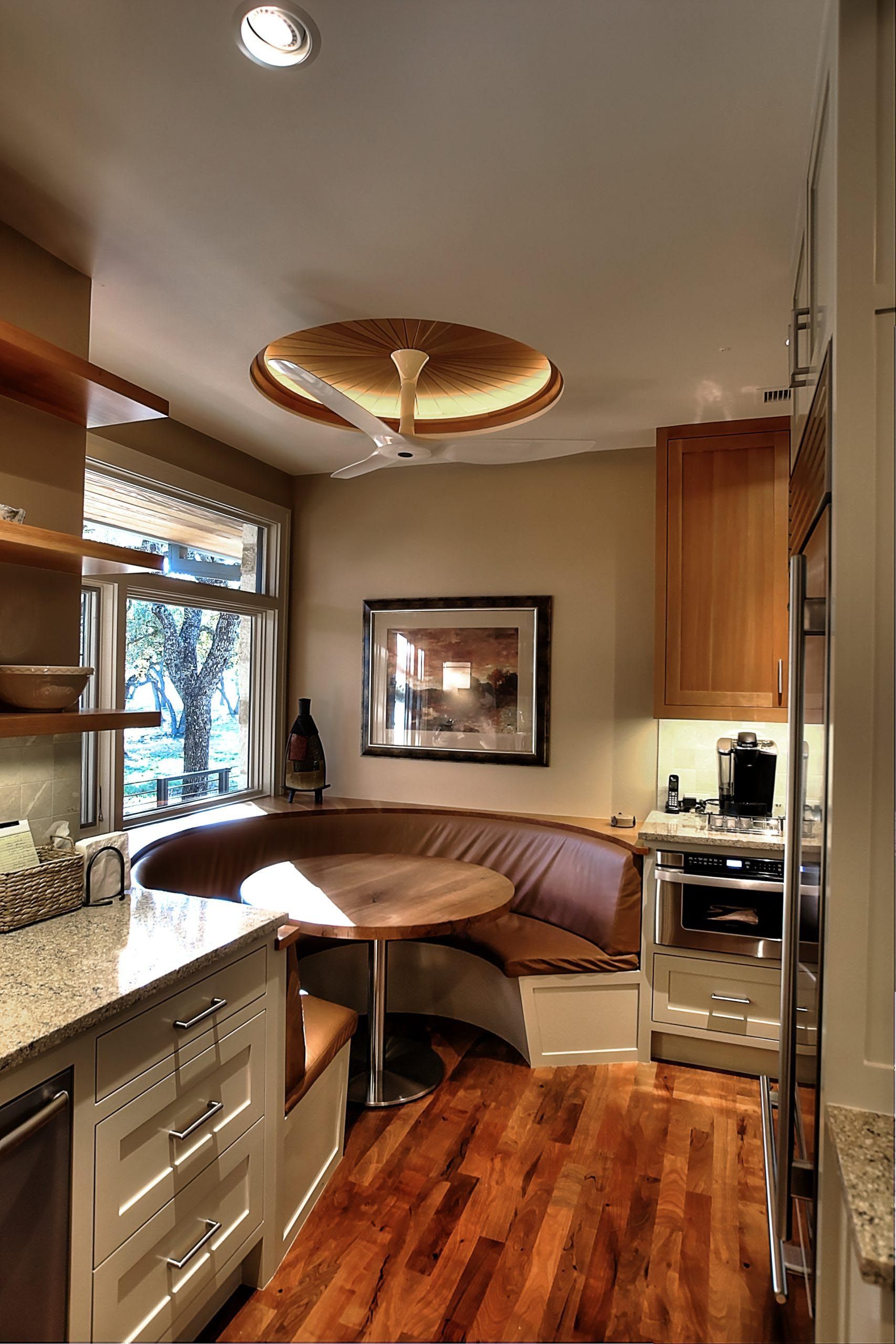 Cozy kitchen with a built-in booth, wooden floors, and a round table.