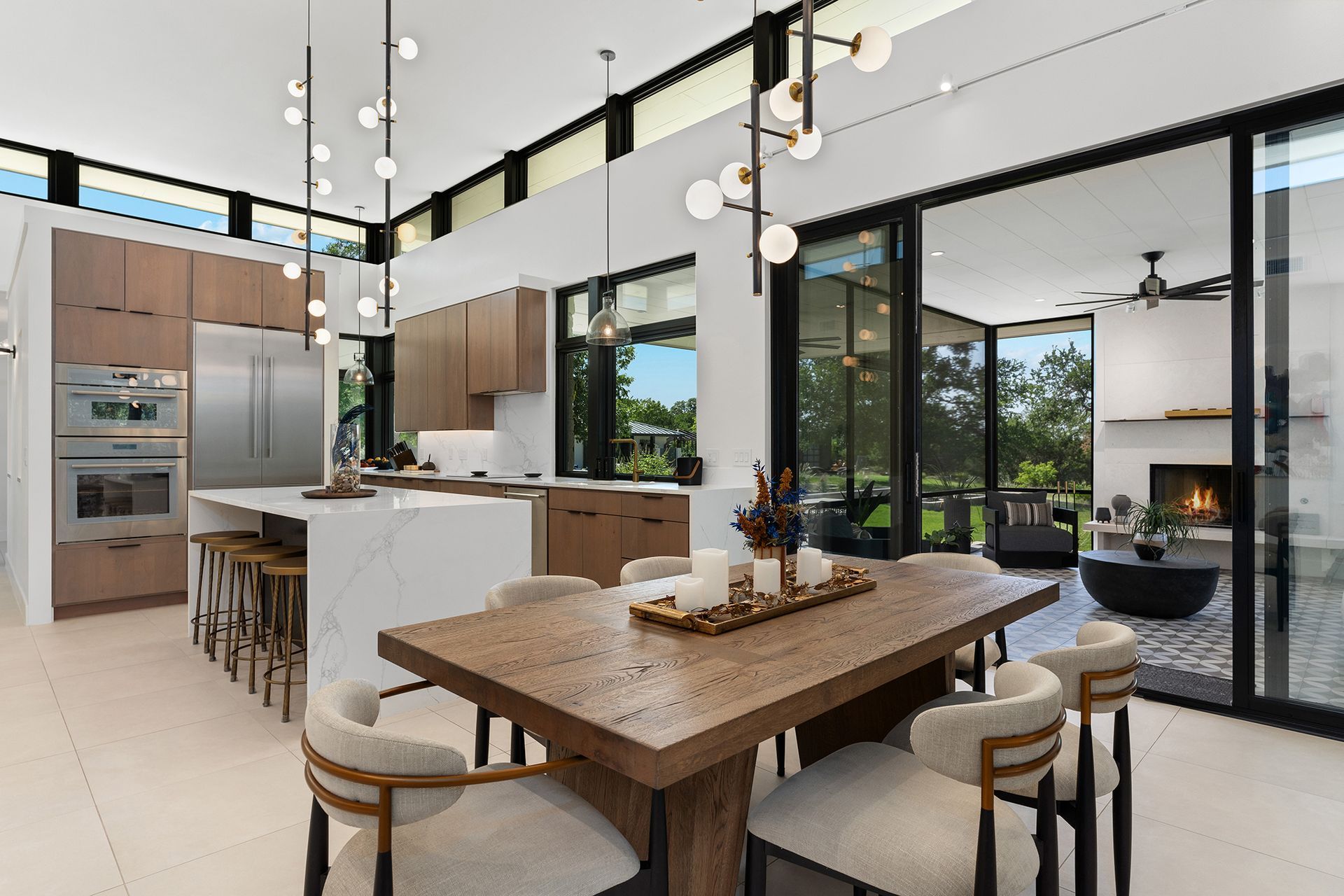 Modern open-plan kitchen and dining area with light wood cabinets, white waterfall island, and large glass patio doors.