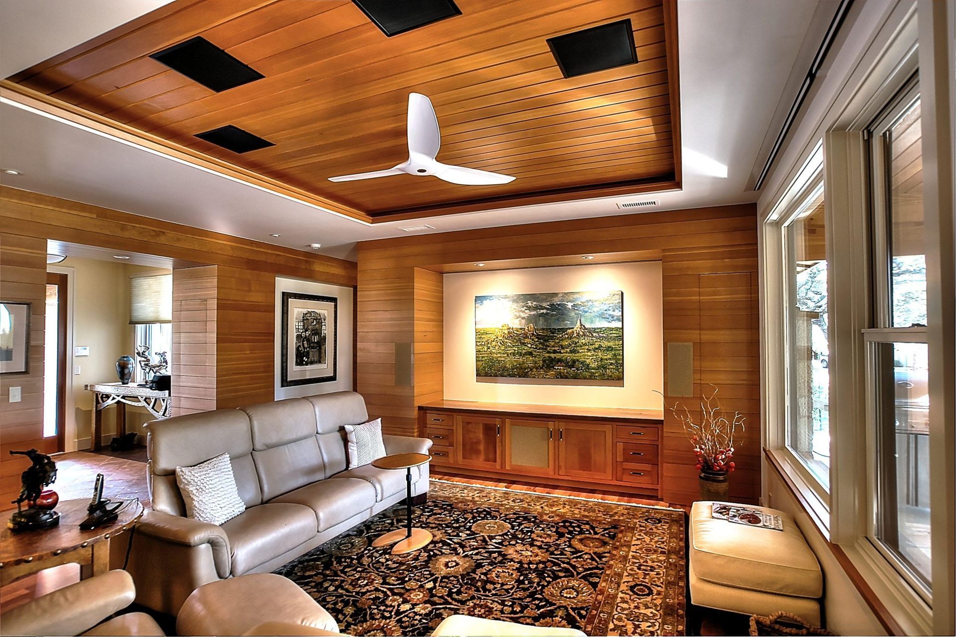 Living room with wooden paneling, a beige sofa, and a ceiling fan.