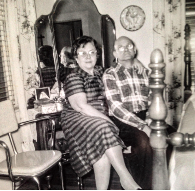 A black and white photo of a man and woman sitting on a bed