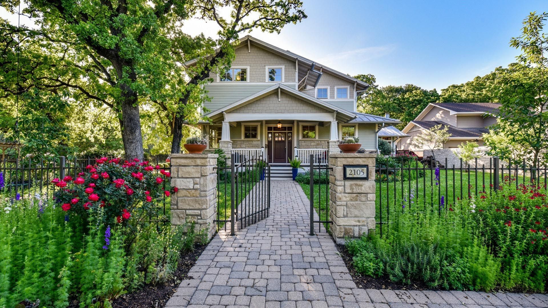 Craftsman-style home with brick walkway, gated entrance, and lush landscaping.