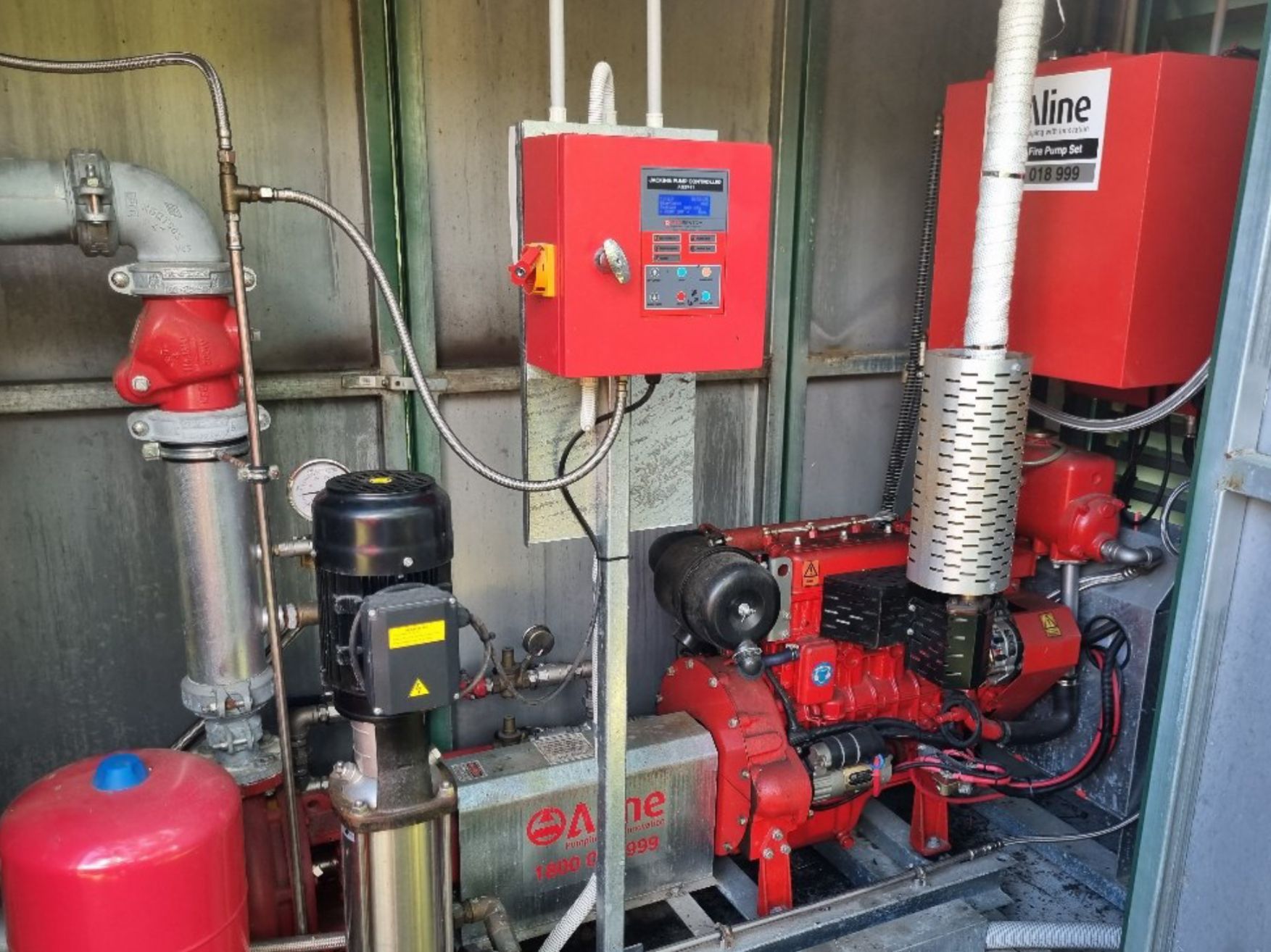 Red Industrial Fire Pump Room With Pumps, Pipes, Control Panel, and Red Pressure Tank — Flaming North Fire Protection Pty Ltd in Garbutt, QLD