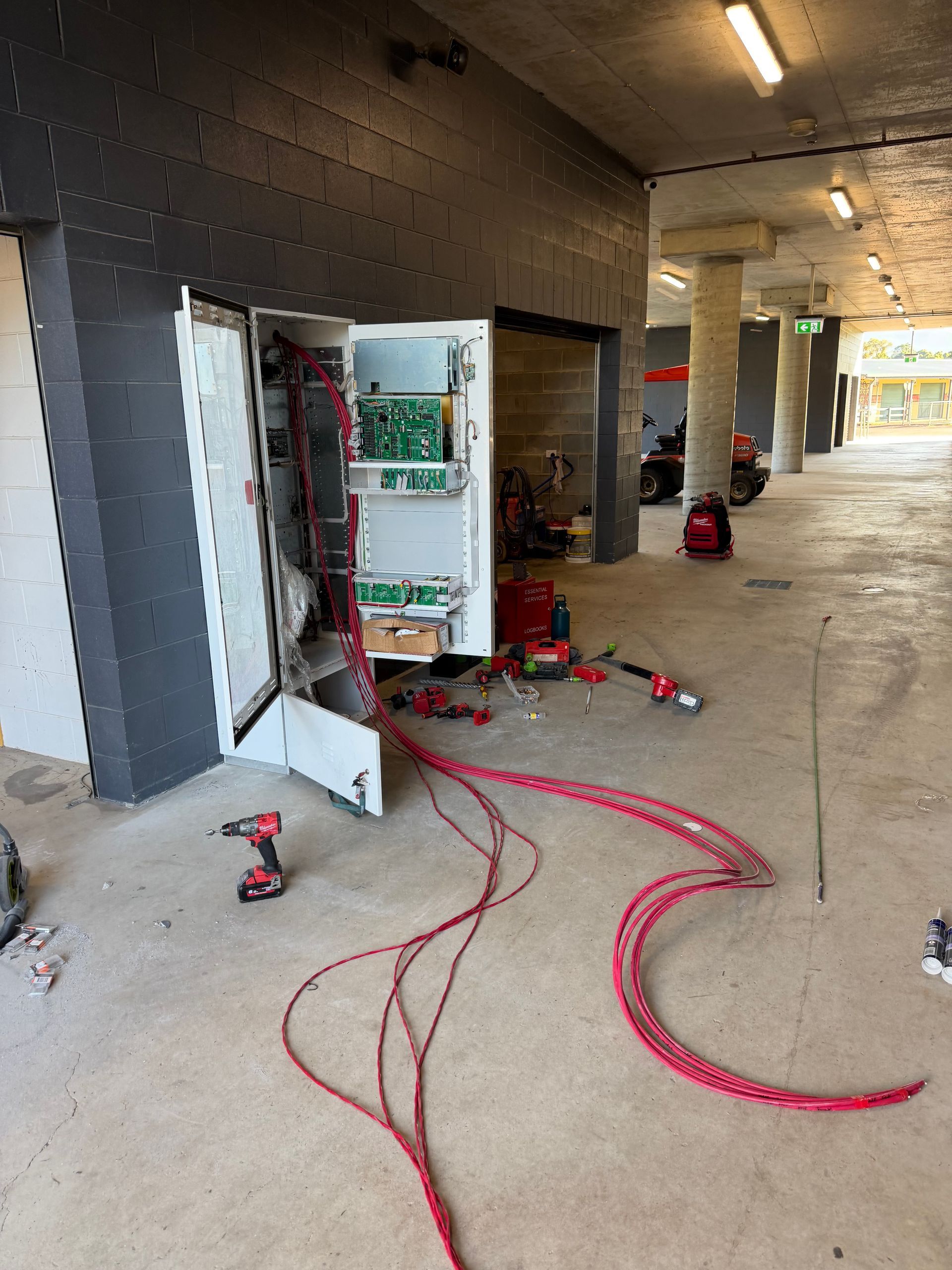 Damaged Electrical Panel With Exposed Wiring and Tools on a Covered Walkway — Flaming North Fire Protection Pty Ltd in Garbutt, QLD