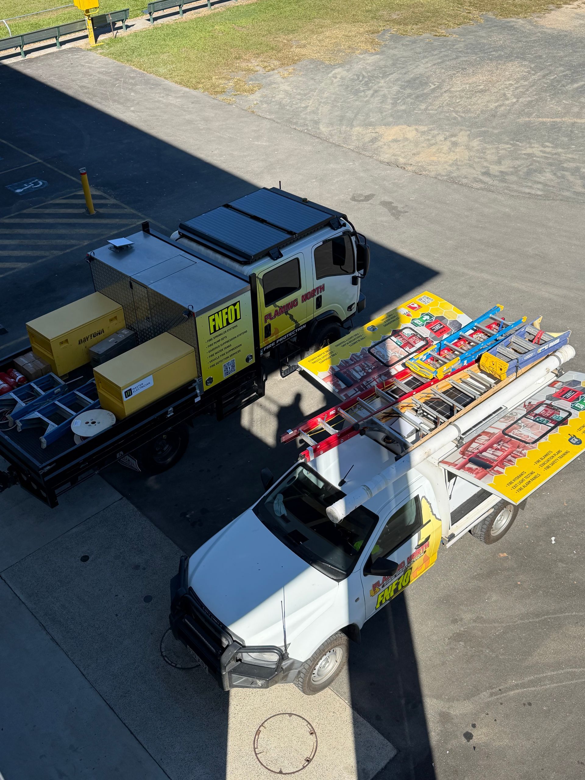 Two Trucks Beside a Warehouse, One Carrying Colourful Stacked Cargo Pallets and Boxes — Flaming North Fire Protection Pty Ltd in Garbutt, QLD