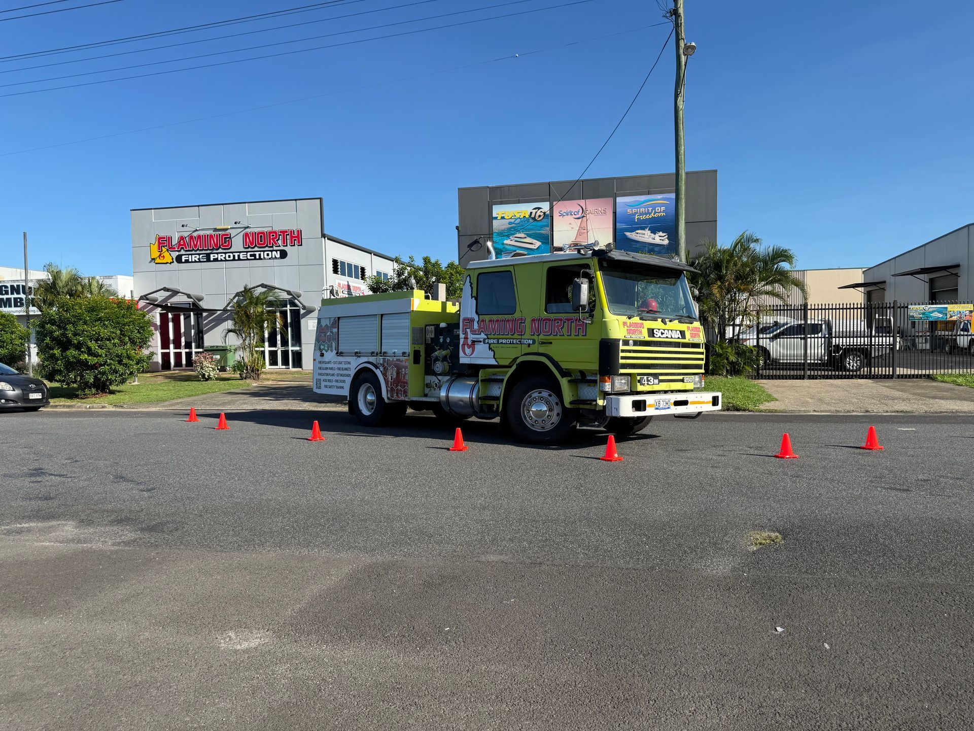 Green And White Truck on a Road Course With Orange Cones in a Parking Lot Under a Clear Blue Sky — Flaming North Fire Protection Pty Ltd in Charters Towers, QLD
